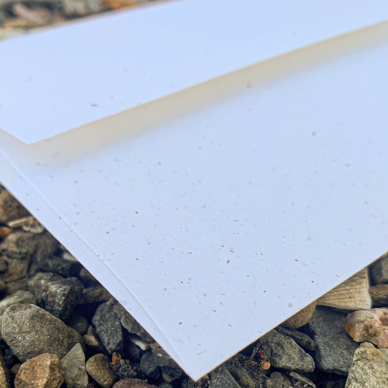 Closeup of square flap on back of cream colored-speckled envelope.