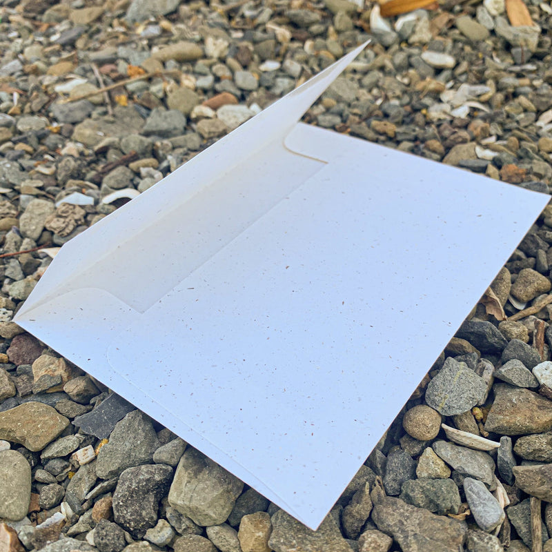 Square flap on back of cream colored-speckled envelope is open at a 45 degree angle.